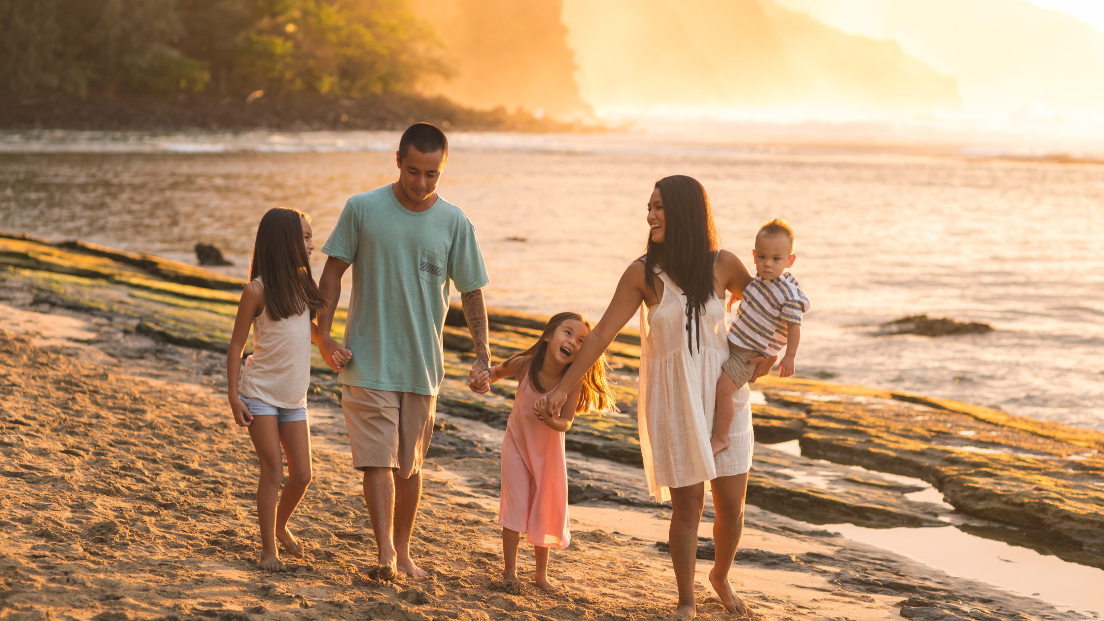 A family of 5 walking hand and hand in the sunset on the Beach.